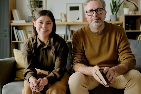 Portrait of young adult woman and middle aged man sitting indoors