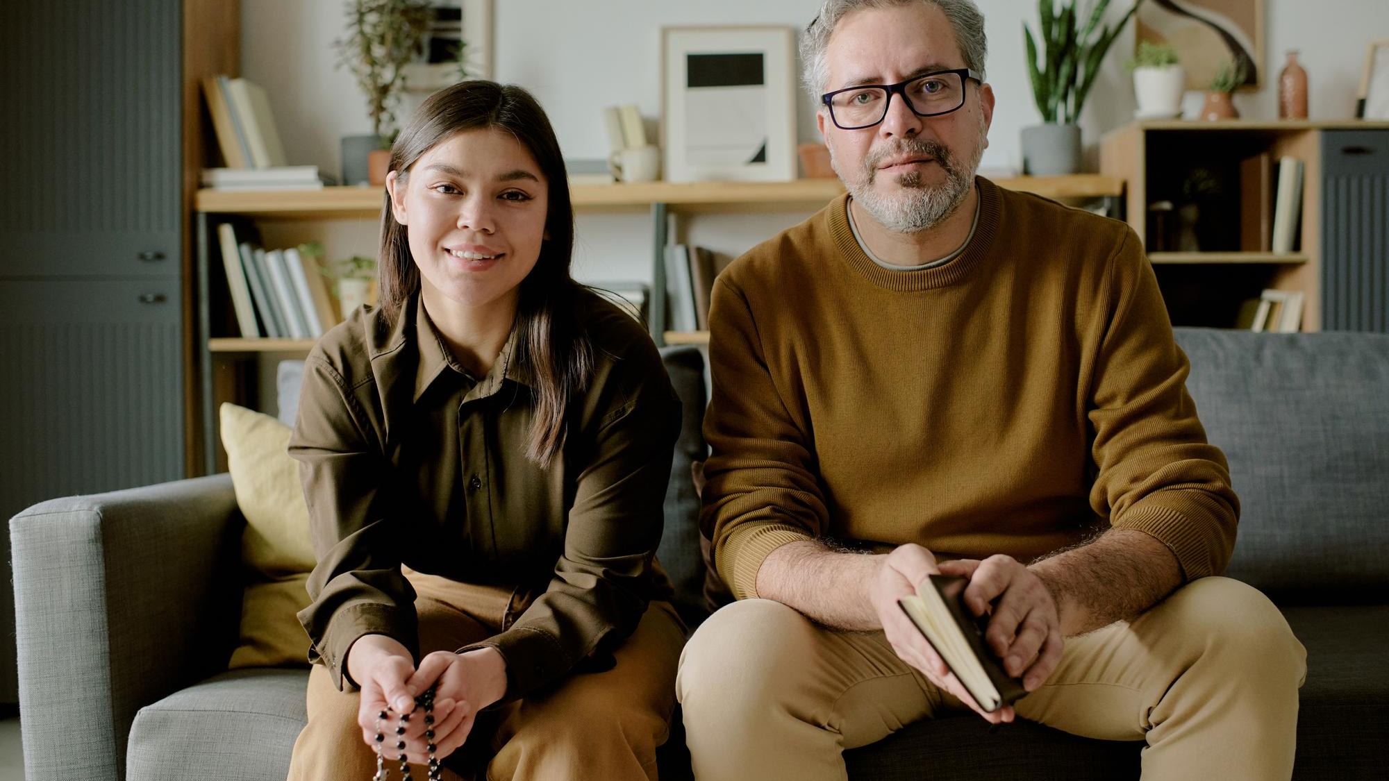 Portrait of young adult woman and middle aged man sitting indoors