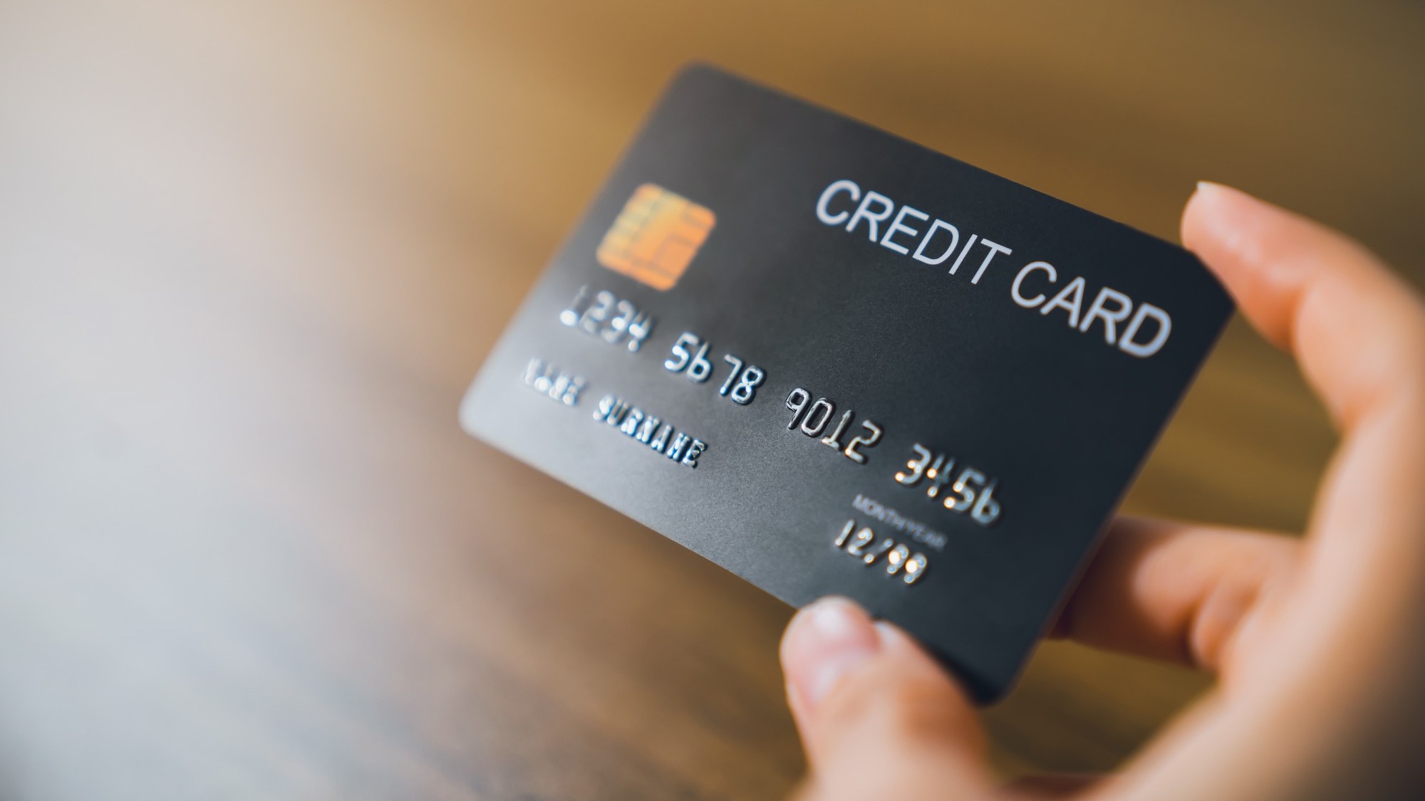 Hand holding credit card on wood table