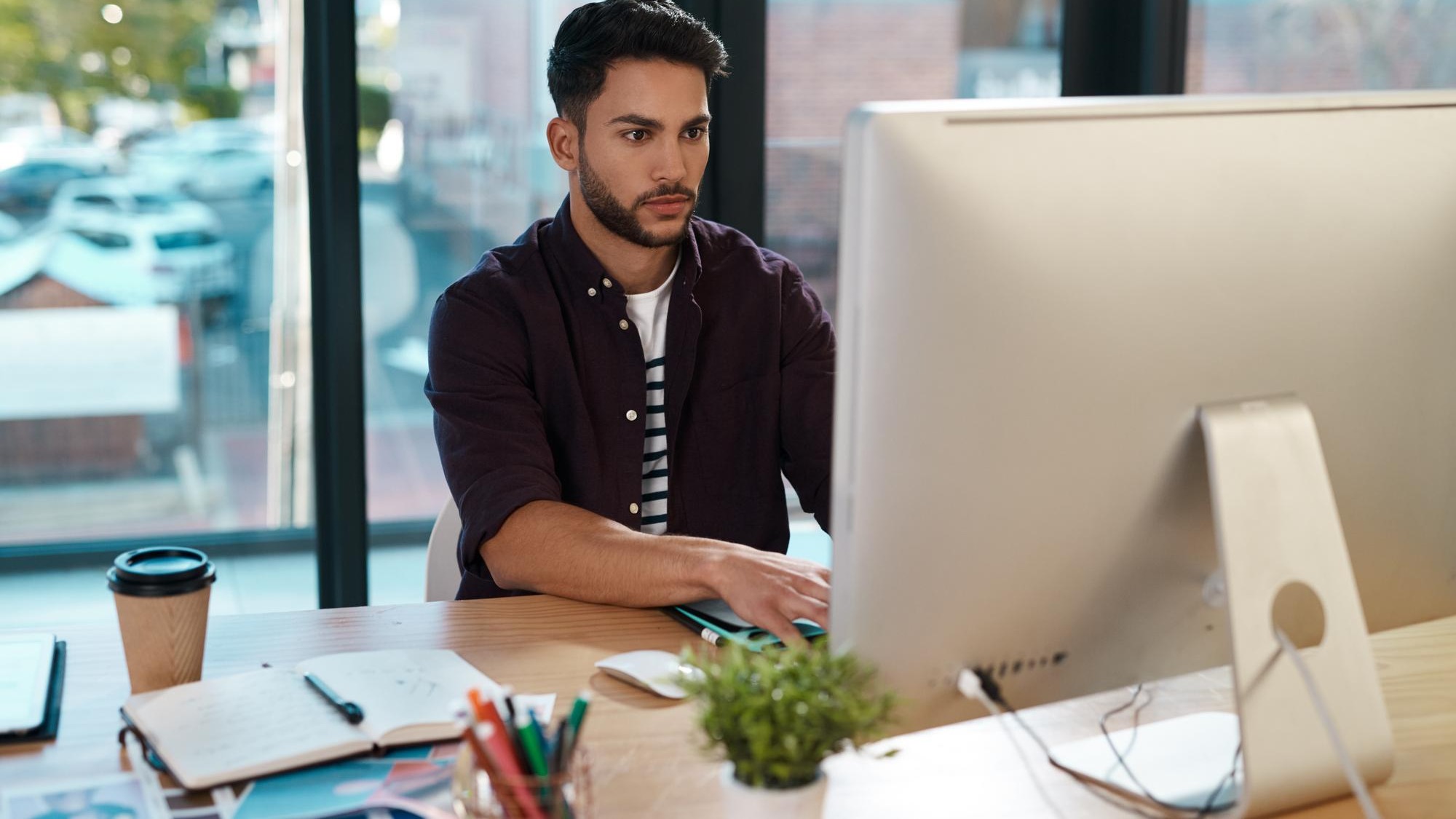 Business computer and man working at a desk while online for research or creative work Male entrepreneur person at workplace with focus and internet connection for designer project or reading email