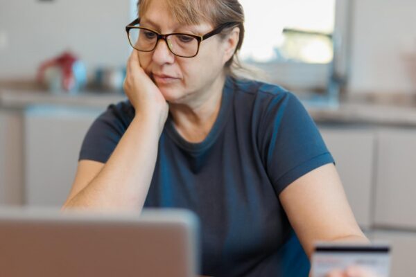 Frustrated Retired Senior Woman Sitting On Sofa At Home Using Laptop
