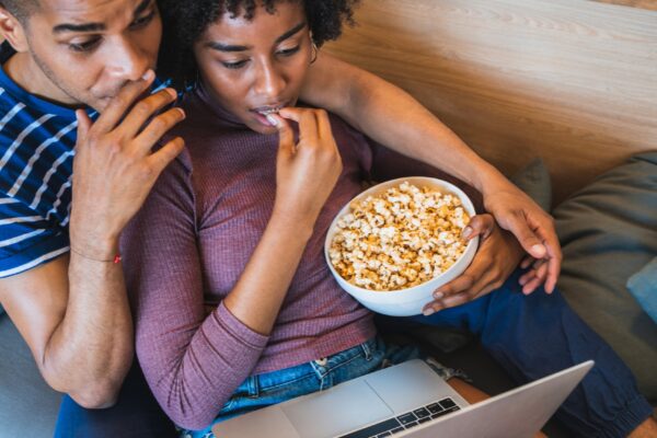 Latin couple watching a movie with laptop at home.