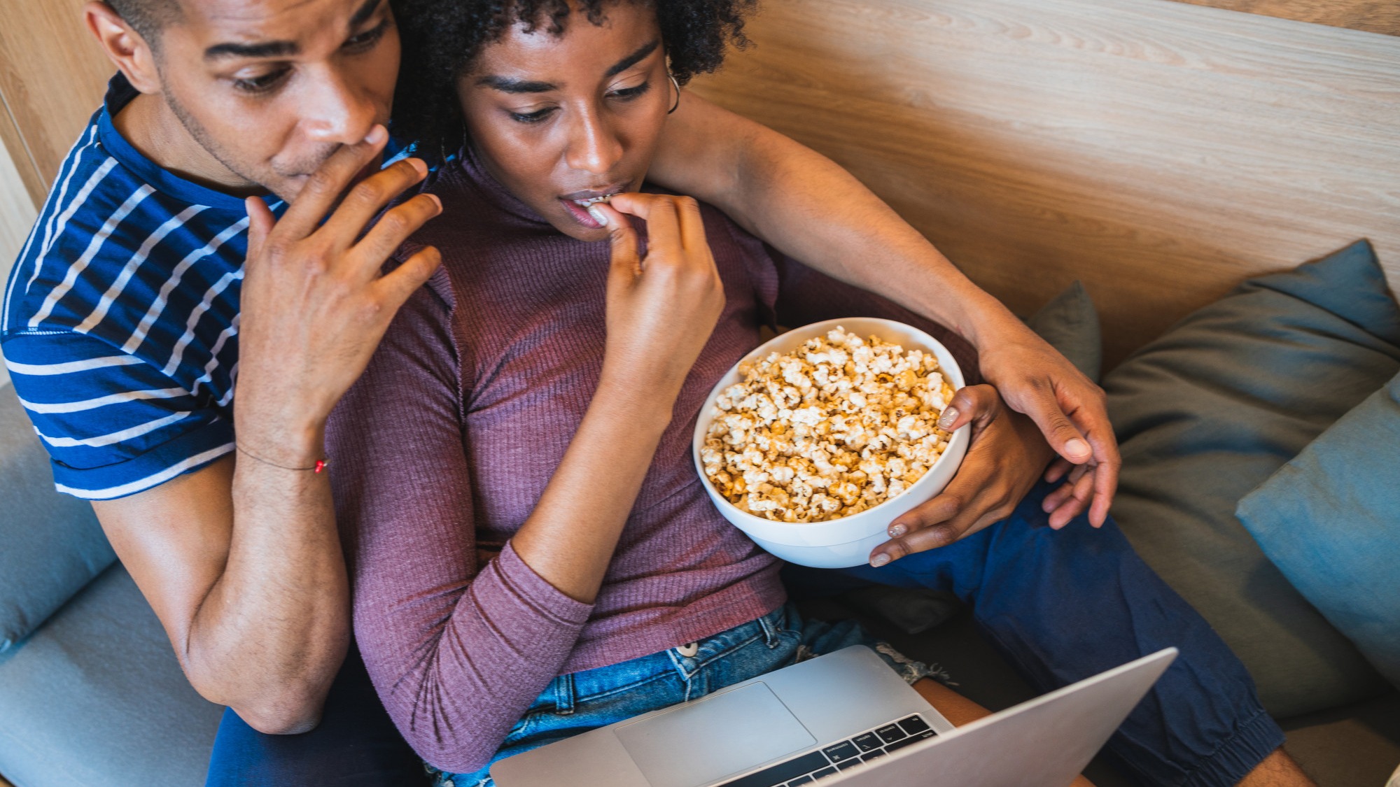 Latin couple watching a movie with laptop at home.