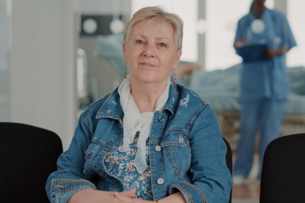 Portrait of senior patient preparing for medical appointment in waiting area. Close up of retired woman sitting in facility reception room to do checkup appointment with physician.