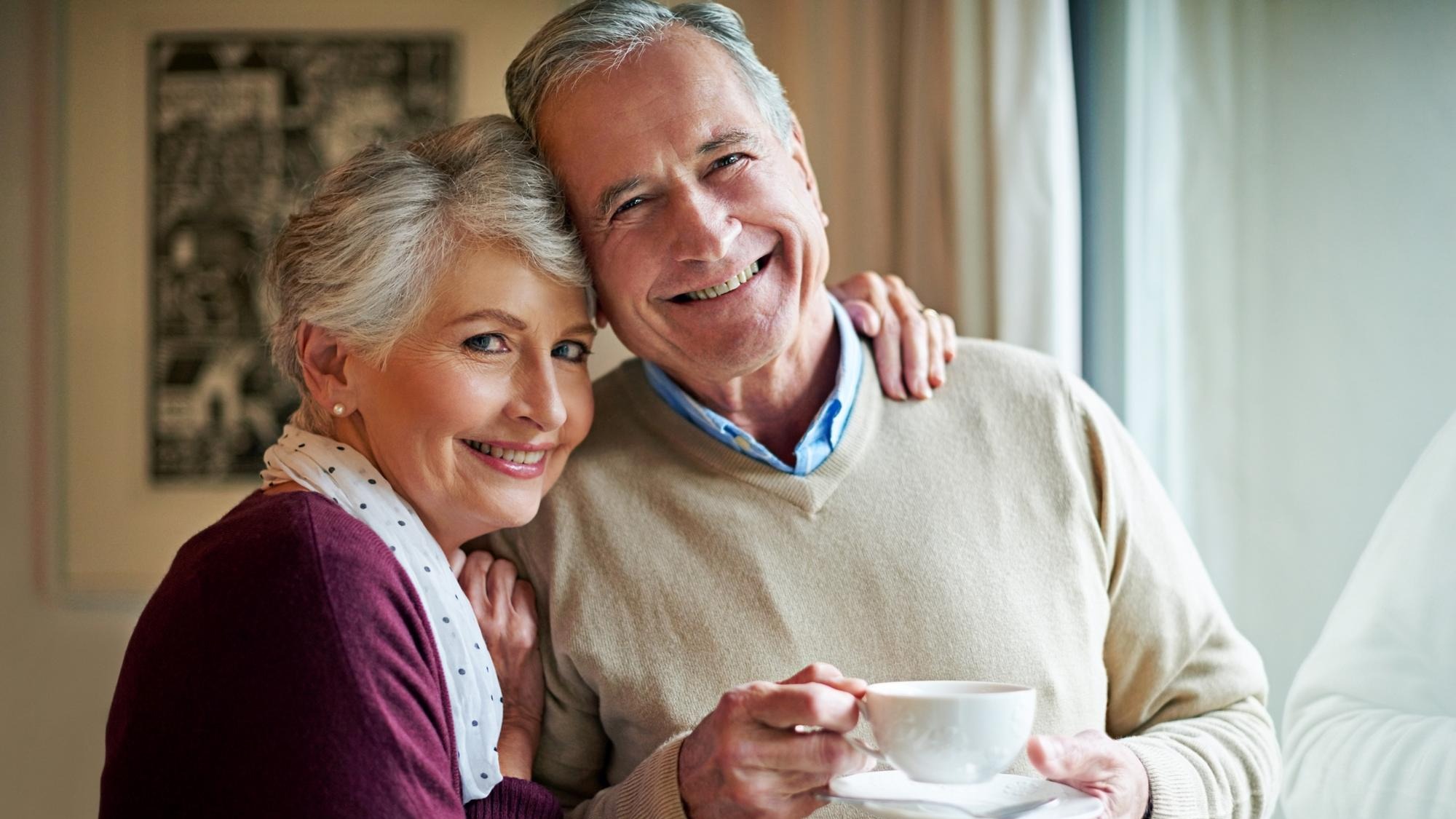 Senior couple tea and window in home for relax love and portrait for married man and woman Living room house and calm for retired people coffee or beverage for romance and peace in Germany