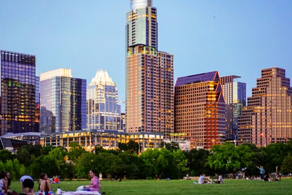 people sitting on green grass field near city buildings during daytime