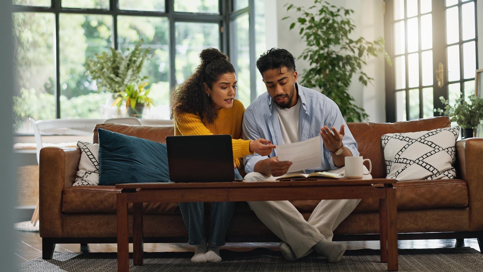 Home couple and discussion with paperwork financial analysis and checking info with laptop or app Asset management online and people with documents in living room bills and planning in house