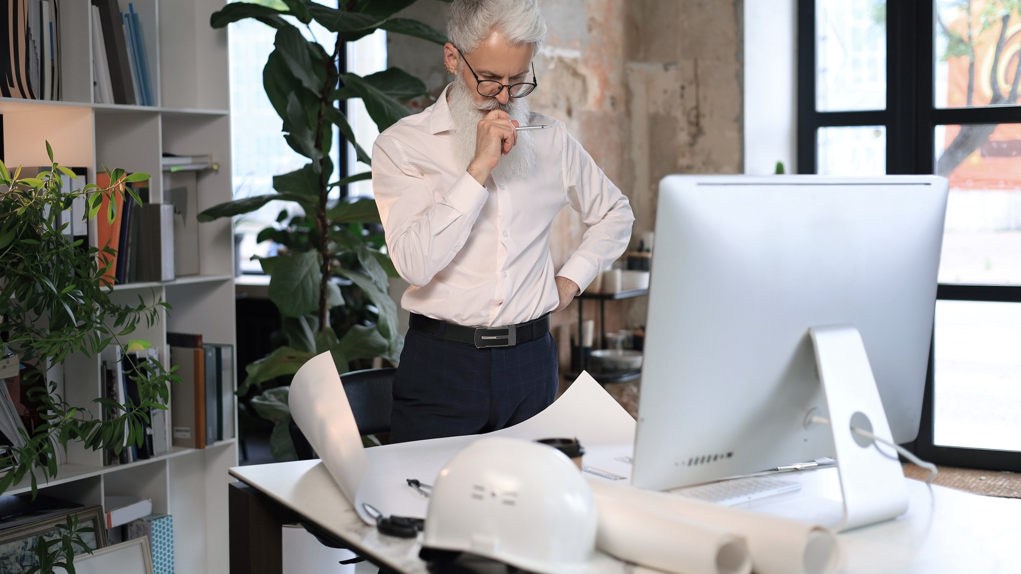 Good looking mature architect drawing something while working in the office.