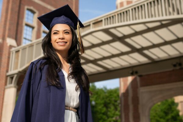 a woman in a cap and gown standing in front of a bridge