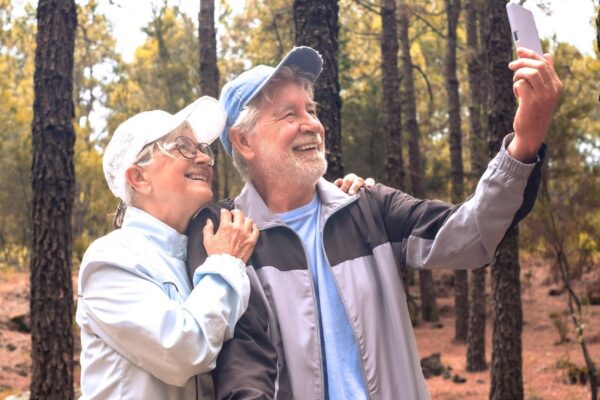 Video call concept Happy bonding senior couple enjoying mountain hike in the forest expressing joy