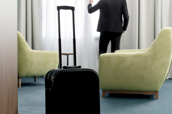 Rear view of businessman wearing dark suit standing in hotel room looking into window