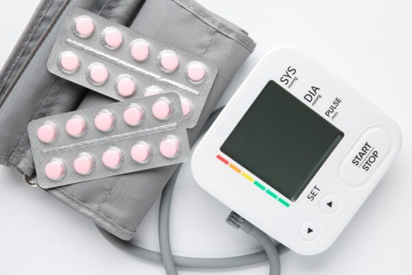 Blood pressure measuring device and pills on white background top view