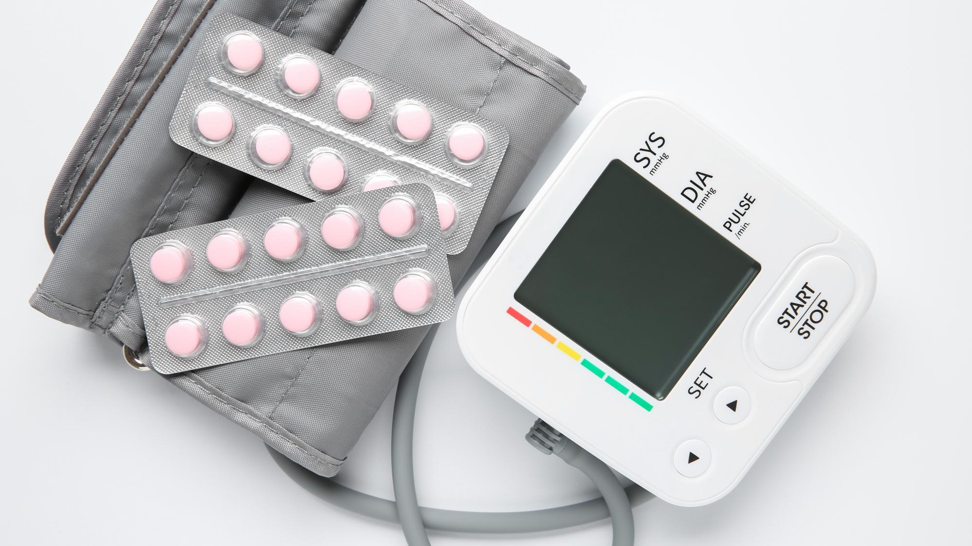 Blood pressure measuring device and pills on white background top view