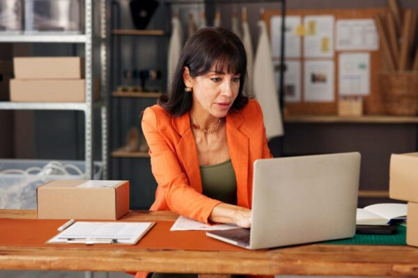 Woman typing and fashion ecommerce with laptop to confirm order schedule shipping and inquiry Mature person pc and online inventory for clothes stock supply chain and logistics report of deliver