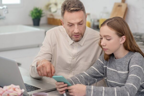 Bearded father pointing something out on his daughters smartphone