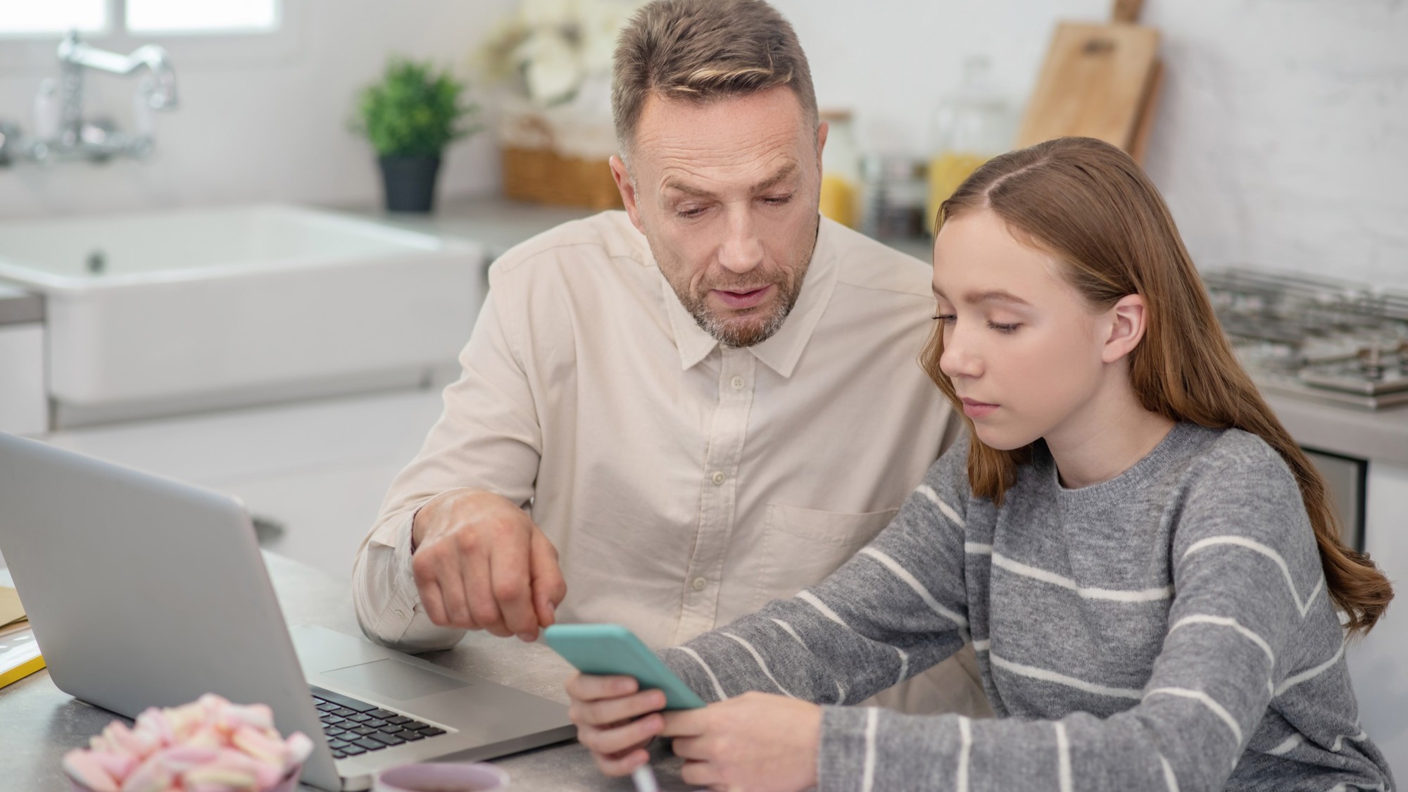 Bearded father pointing something out on his daughters smartphone