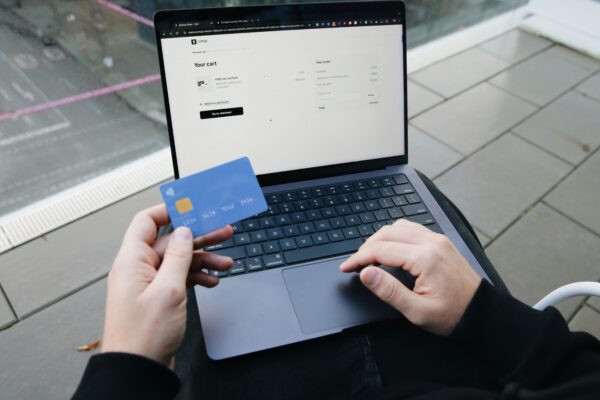 A person sitting in a chair with a laptop and a credit card