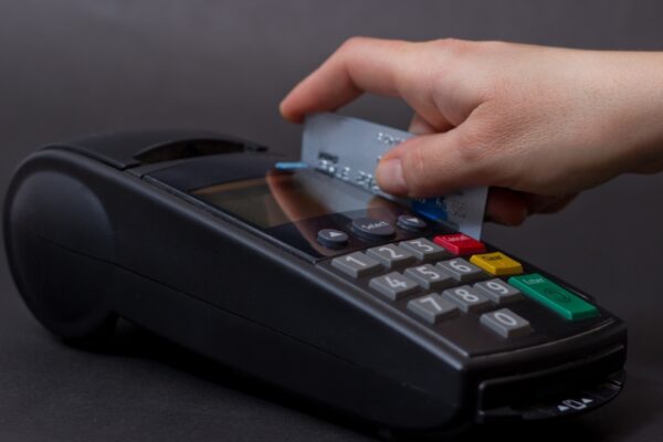 Hand Swiping Credit Card In Store. Female hands with credit card and bank terminal. Color image of a POS and credit cards.