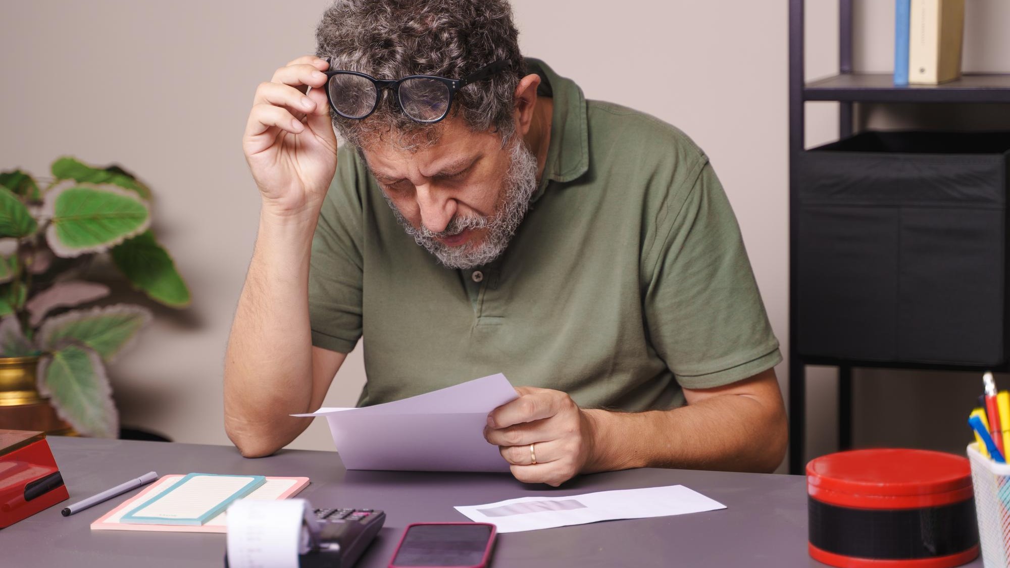 A fifty-year-old man with myopia lifts his glasses to closely read a letter