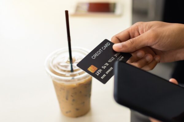 Man hand holding credit card with smartphone in coffee cafe.