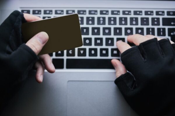 Typing credit card and hands of hacker for cyber crime financial fraud and cloning for identity theft or breach Person dark and online for hacking or malware attack phishing and account takeover