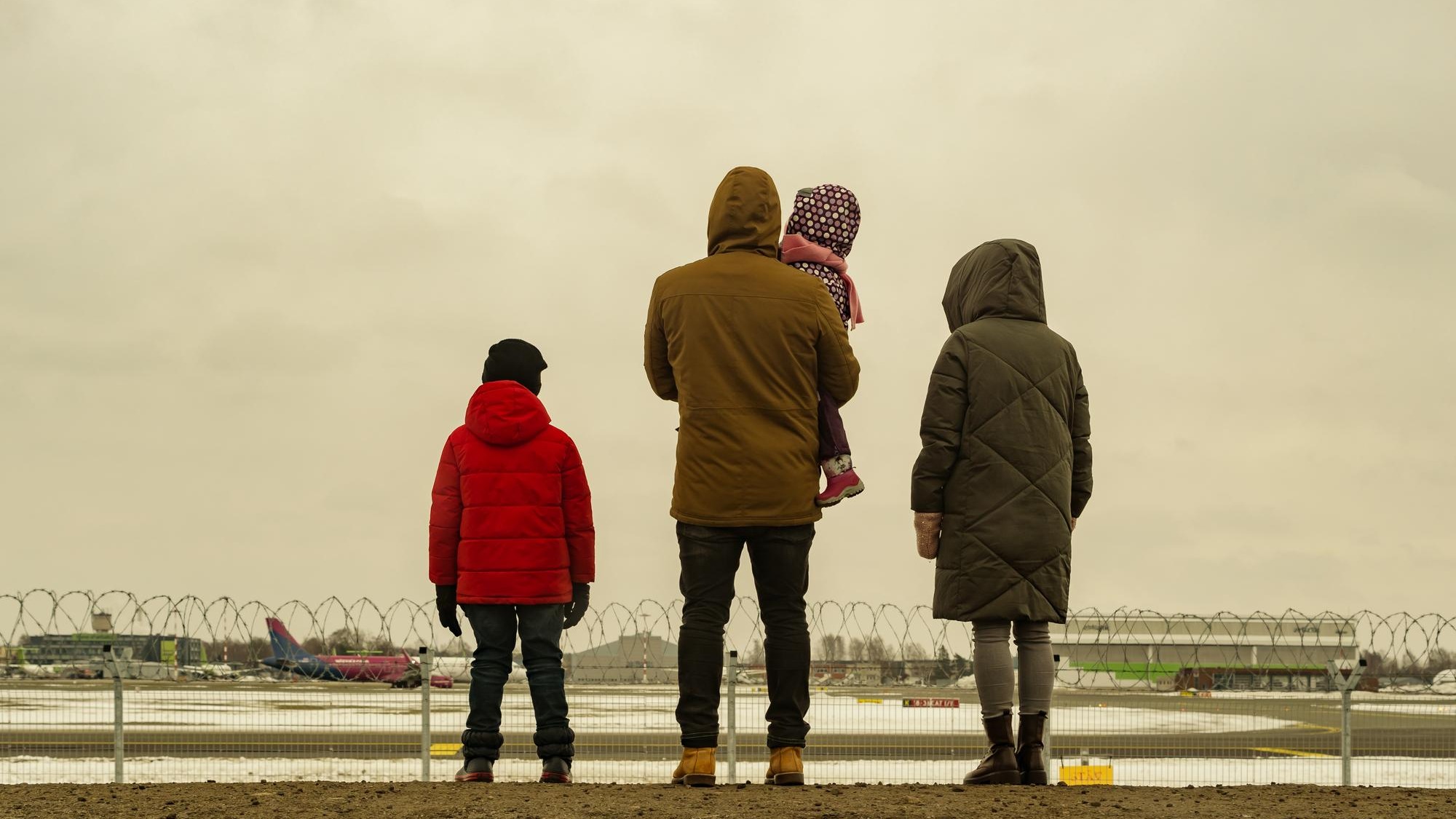 Family together is watching planes take off and landing next to airport