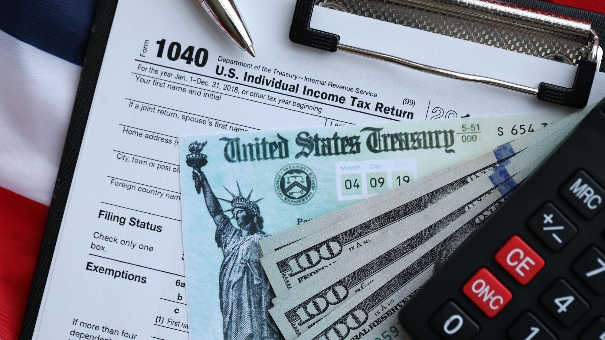 United States 1040 tax form individual income tax return with refund check and US dollar bills