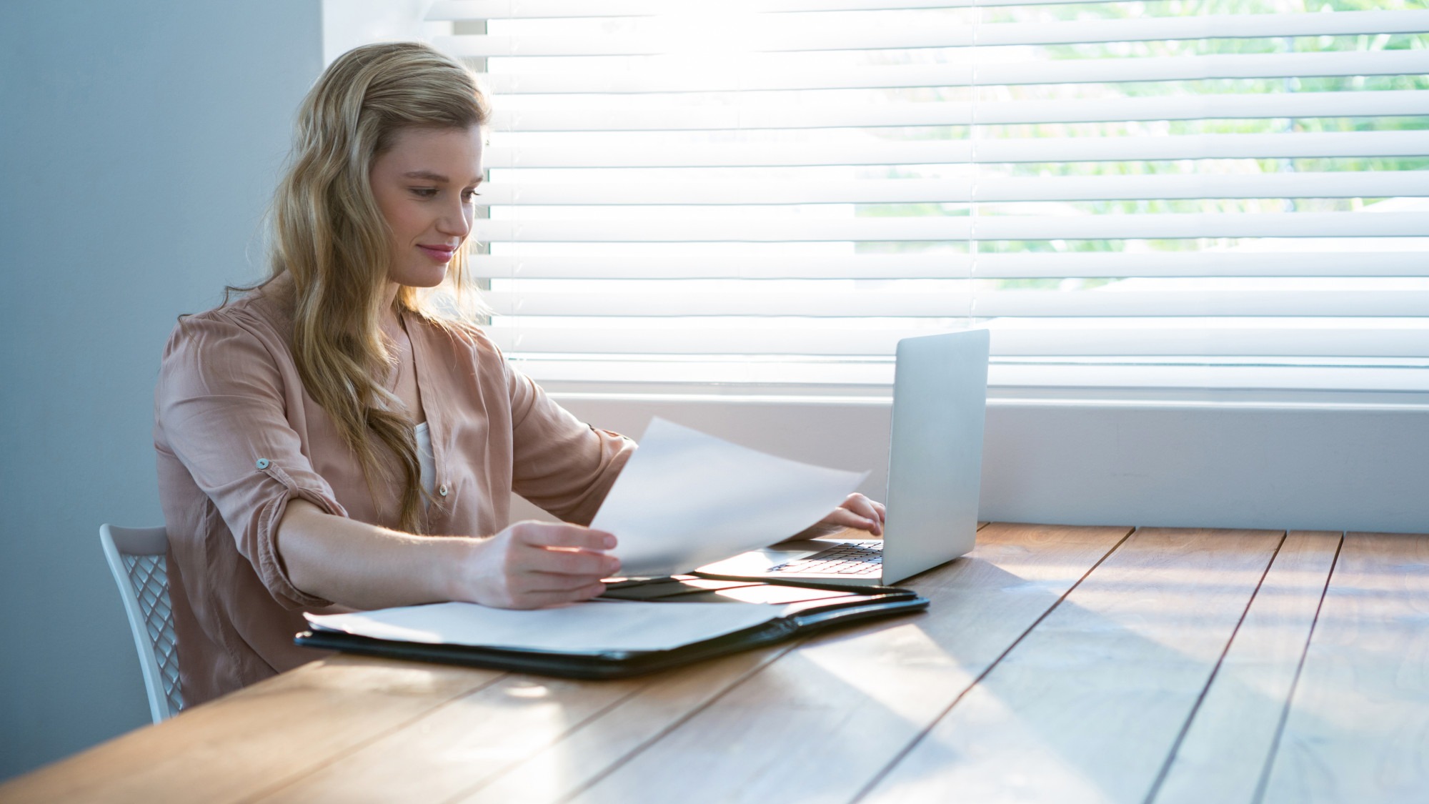 Woman looking at bill while using laptop