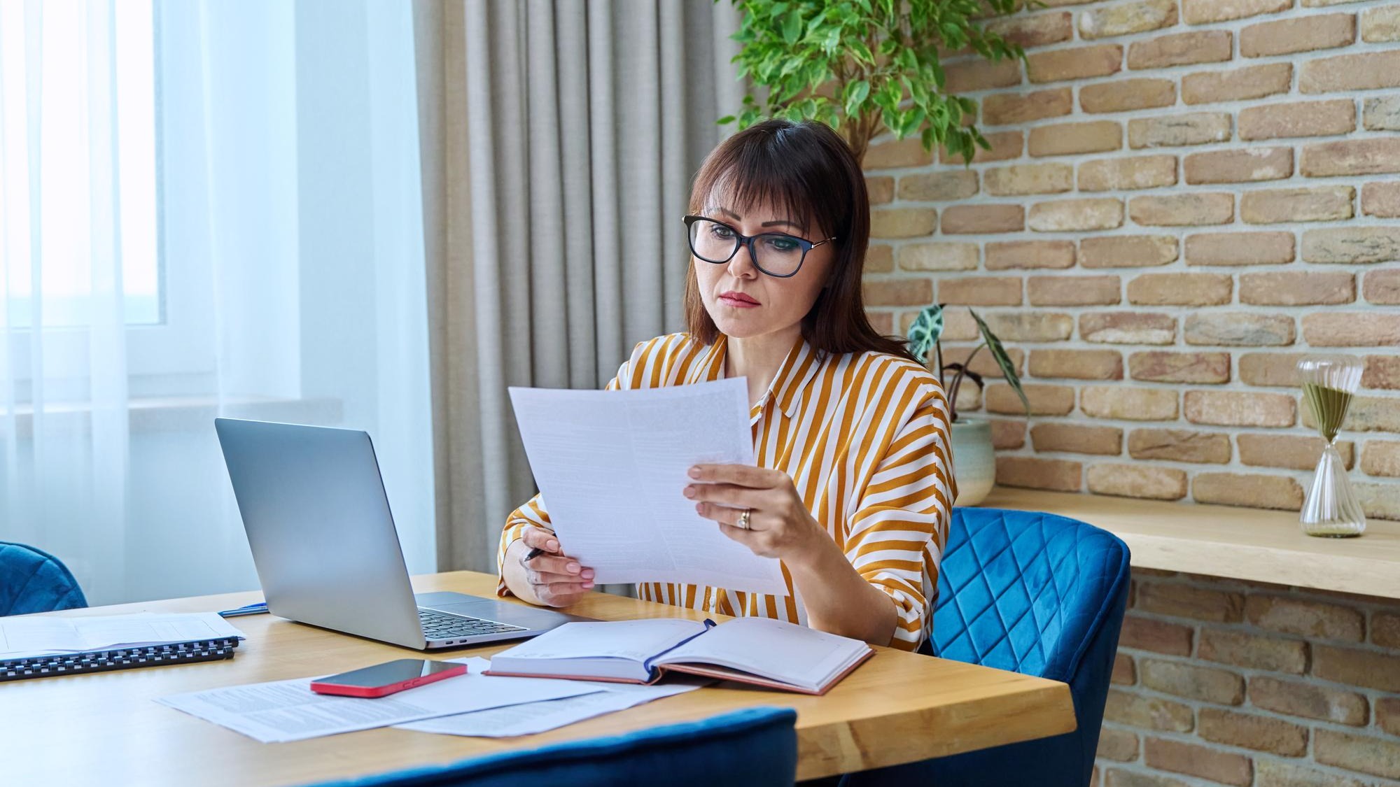 Mature business woman working at desk in home office using laptop
