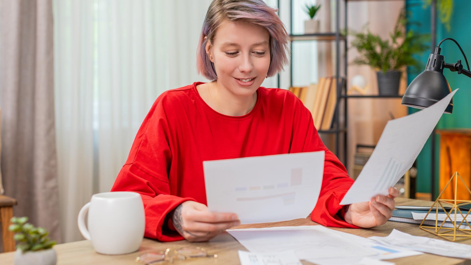 Young woman happily reviewing financial documents nodding positively satisfied successful results