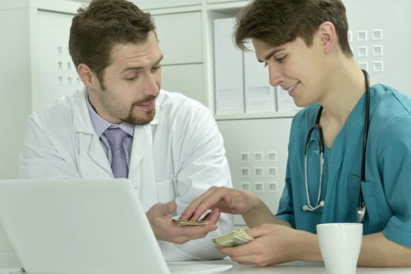 Two male doctors with money in medical office