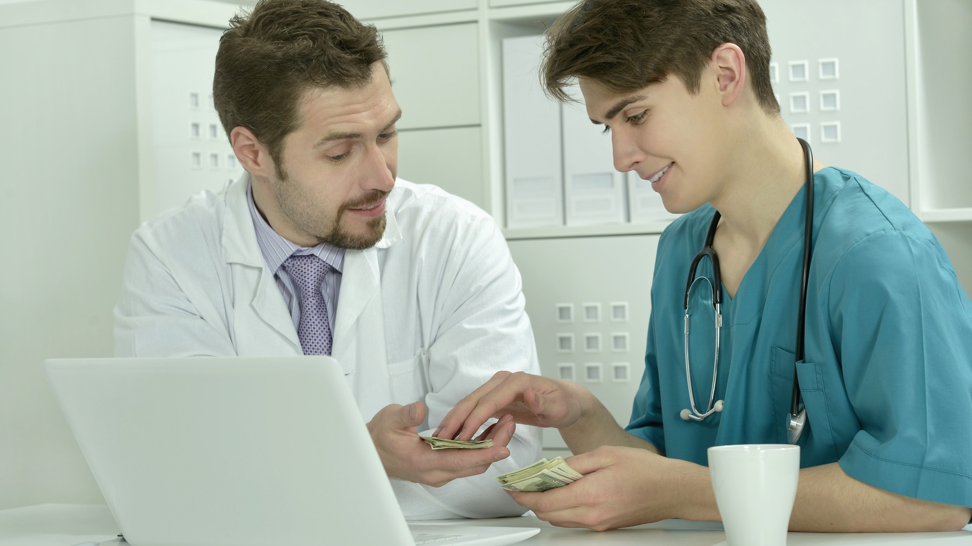 Two male doctors with money in medical office