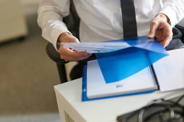 a man in a white shirt and tie holding a folder