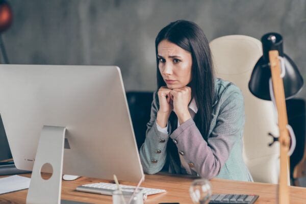 Photo of frustrated scared girl economist representative sit table desk work remote wait for executive job loss notification wear formal suit blazer jacket in workplace workstation