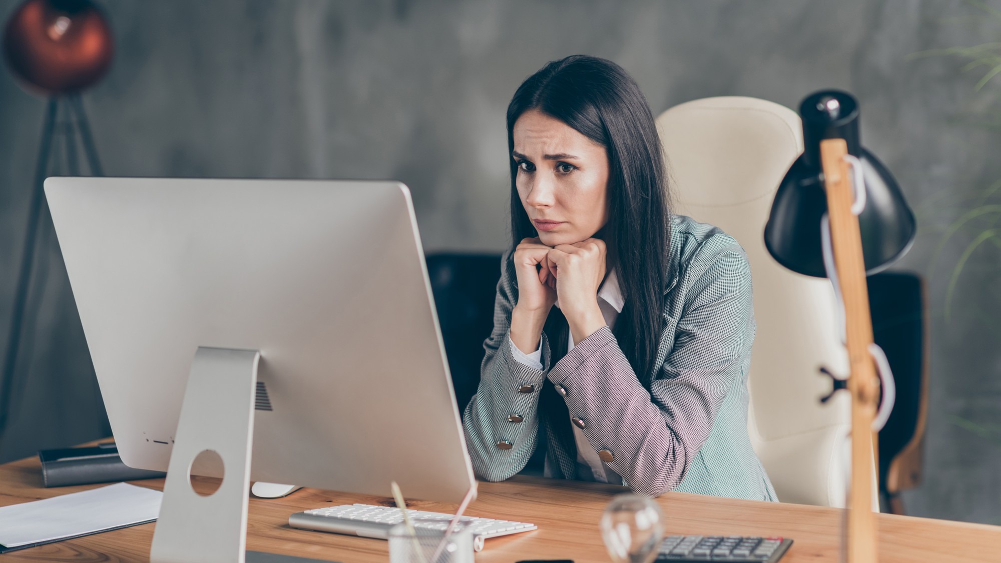 Photo of frustrated scared girl economist representative sit table desk work remote wait for executive job loss notification wear formal suit blazer jacket in workplace workstation