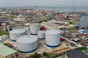 Large industrial tanks sit near a cityscape.