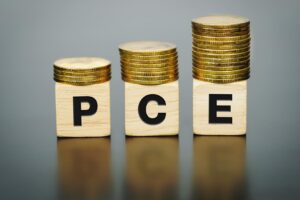 Text PCE (Personal Consumption Expenditure)on wood cube with coins, economic data concept.
