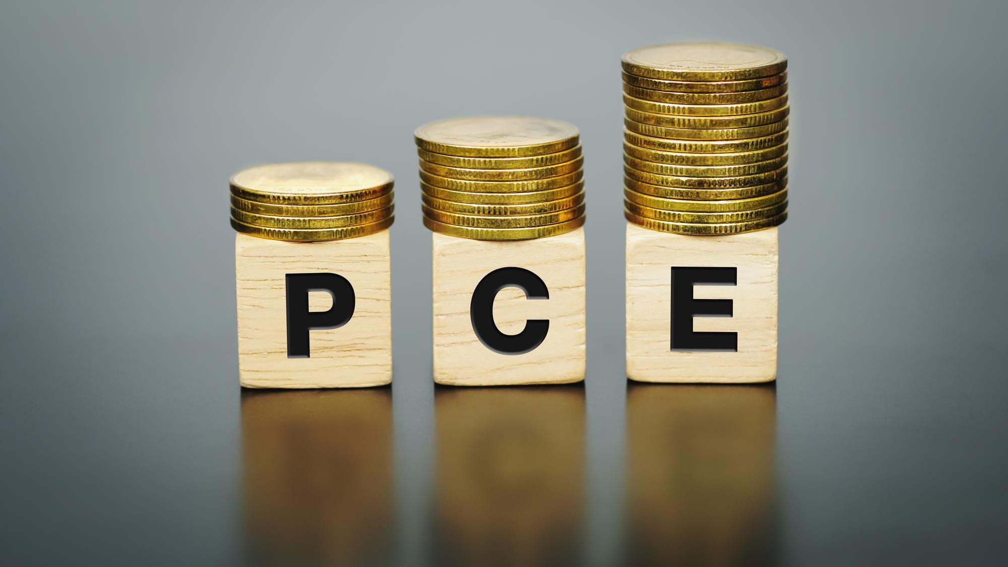 Text PCE (Personal Consumption Expenditure)on wood cube with coins, economic data concept.
