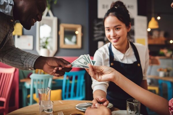 Closeup of customer paying to a waitress in a cafe