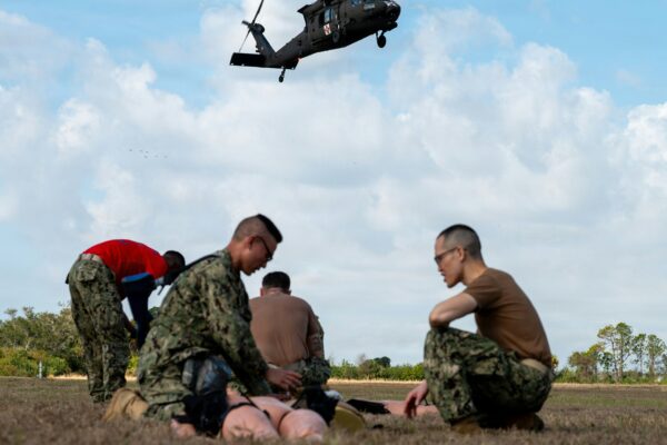 Military personnel practice medical evacuation training with helicopter.