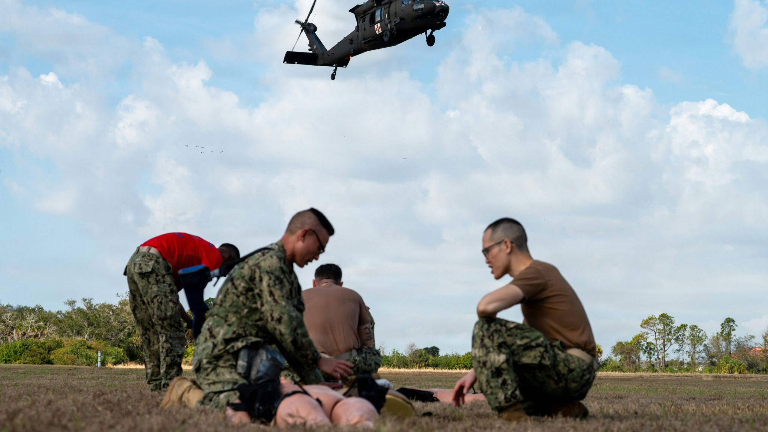 Military personnel practice medical evacuation training with helicopter.