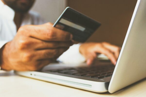 person using laptop computer holding card