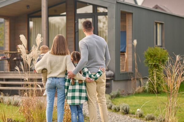 Back view of family hugging and admiring their home
