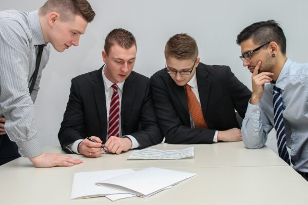 four men looking to the paper on table