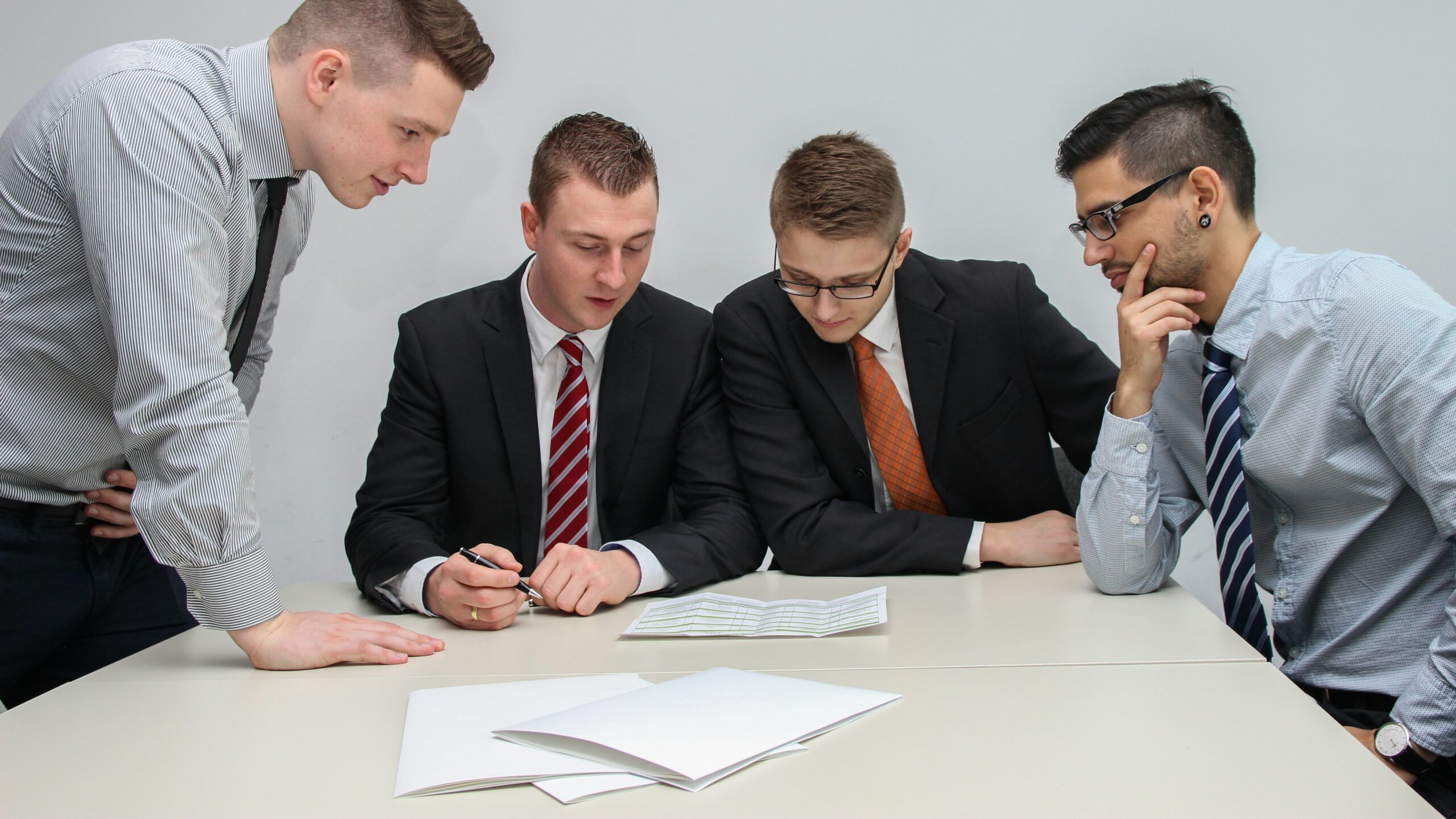 four men looking to the paper on table