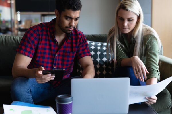 Two diverse business people working in creative office. two people sitting and using laptop. business people and work colleagues at a busy creative office.