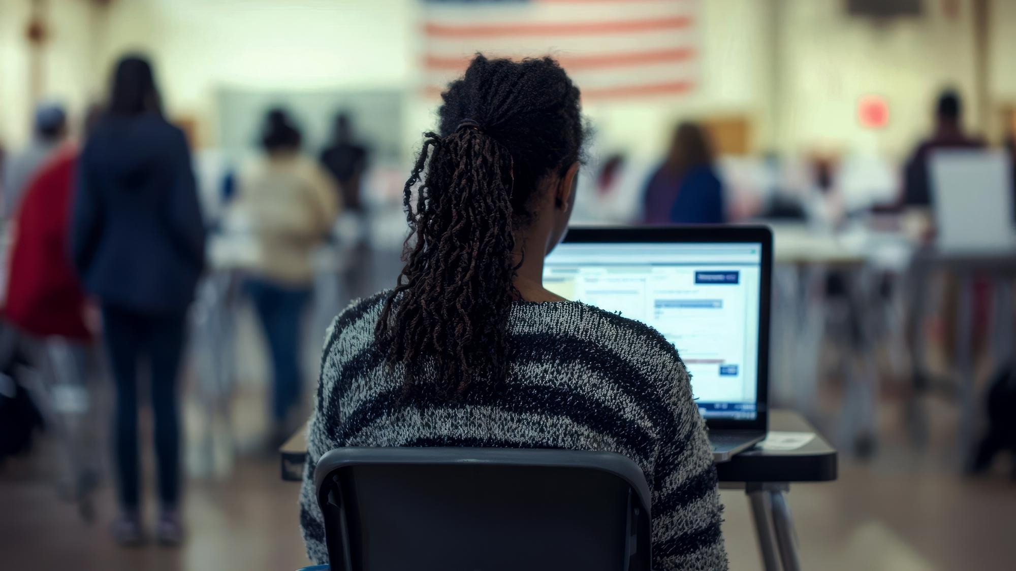 Happy volunteer with laptop to a voter at polling place during US elections