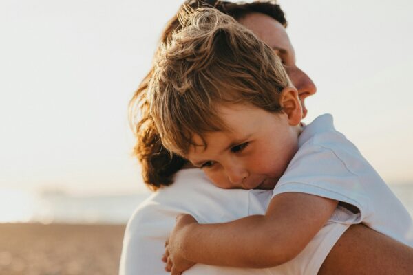 boy hugging woman during daytime