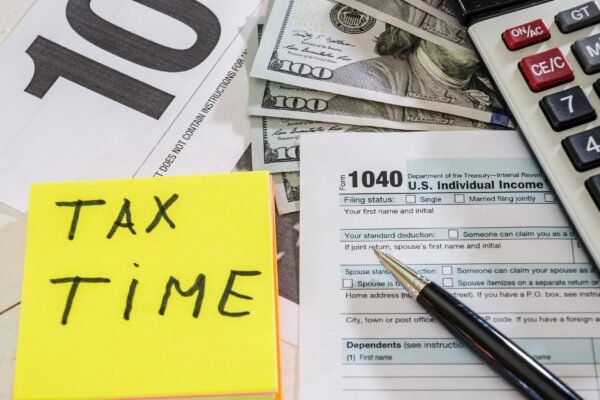 tax forms with dollars pen and calculator