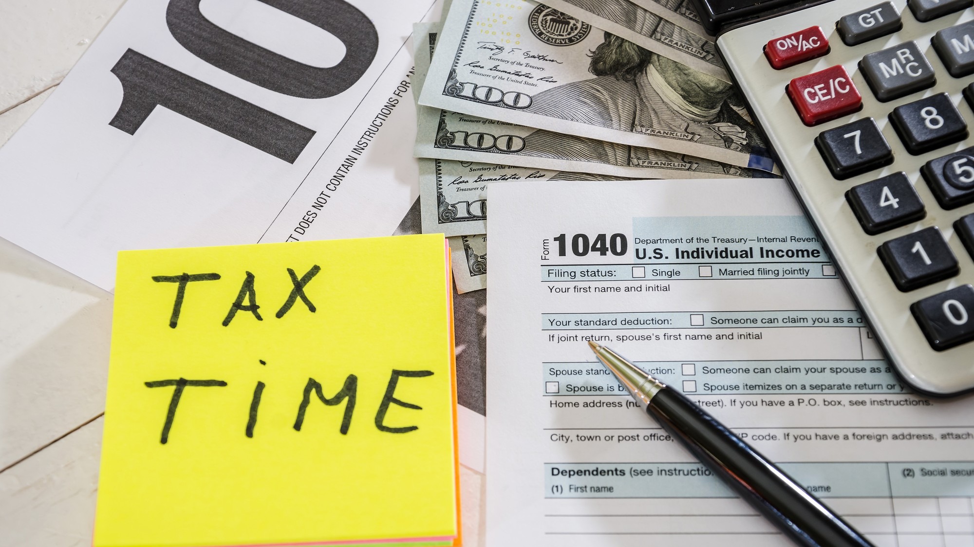 tax forms with dollars pen and calculator